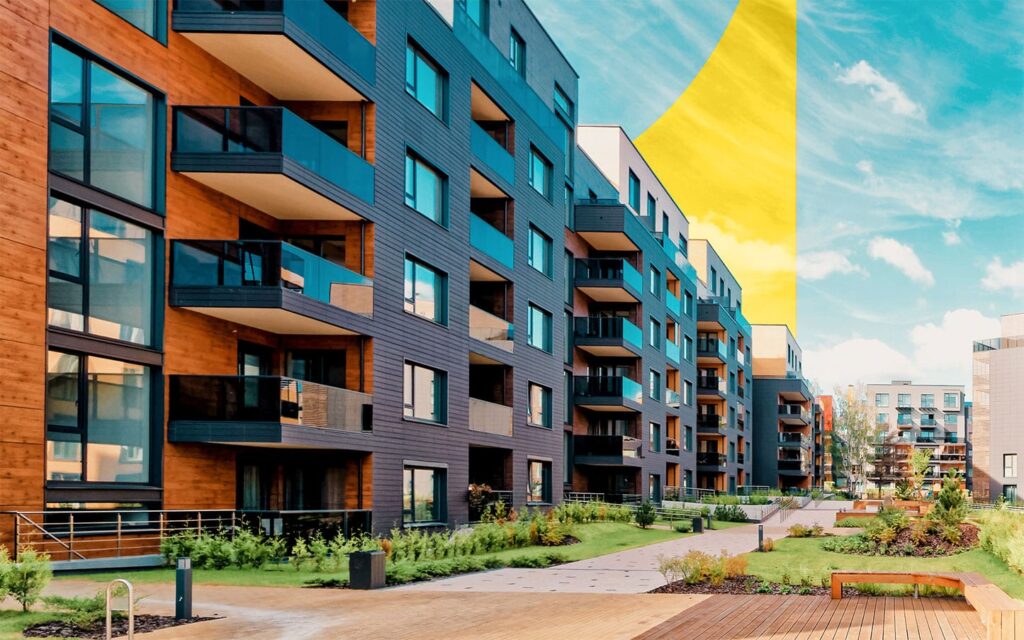 Photo of modern apartment buildings with wood and dark panel exteriors, large glass balconies, and landscaped courtyard under a bright blue sky.